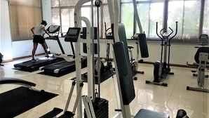 Ein Fitnessstudio mit Laufbändern, Kraftgeräten und einer Bank.