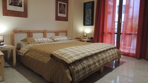 Un dormitorio con una cama doble, un escritorio con lámpara y dos cuadros en la pared.