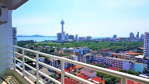 A balcony with a view of a cityscape, including a prominent tower and a body of water in the distance. - Sea View 1 bed Apartment (Pattaya)