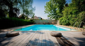 Una piscina al aire libre, sillones reclinables de piscina