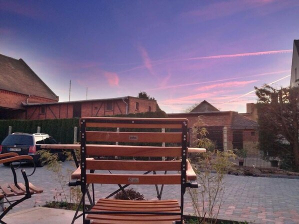 A wooden bench in a courtyard with brick buildings in the background. - Aparthotel Flughafen Leipzig (Schkeuditz)