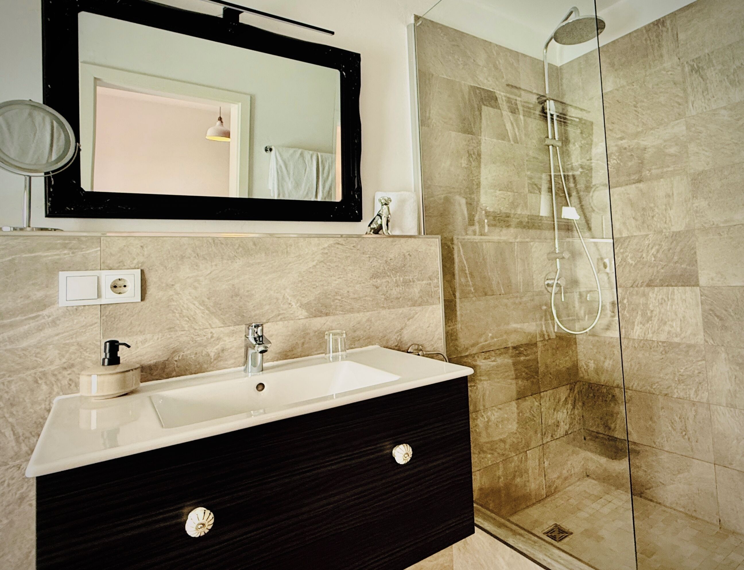 Un baño con lavamanos, espejo y ducha.
