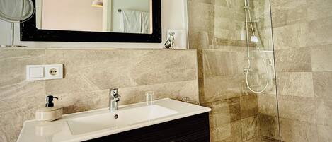 Un baño con lavamanos, espejo y ducha.