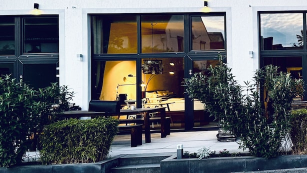 A modern building with large windows, outdoor seating, and well-maintained landscaping. - Aparthotel Flughafen Leipzig (Schkeuditz)