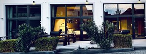 A modern building with large windows, outdoor seating, and well-maintained landscaping. - Aparthotel Flughafen Leipzig (Schkeuditz)