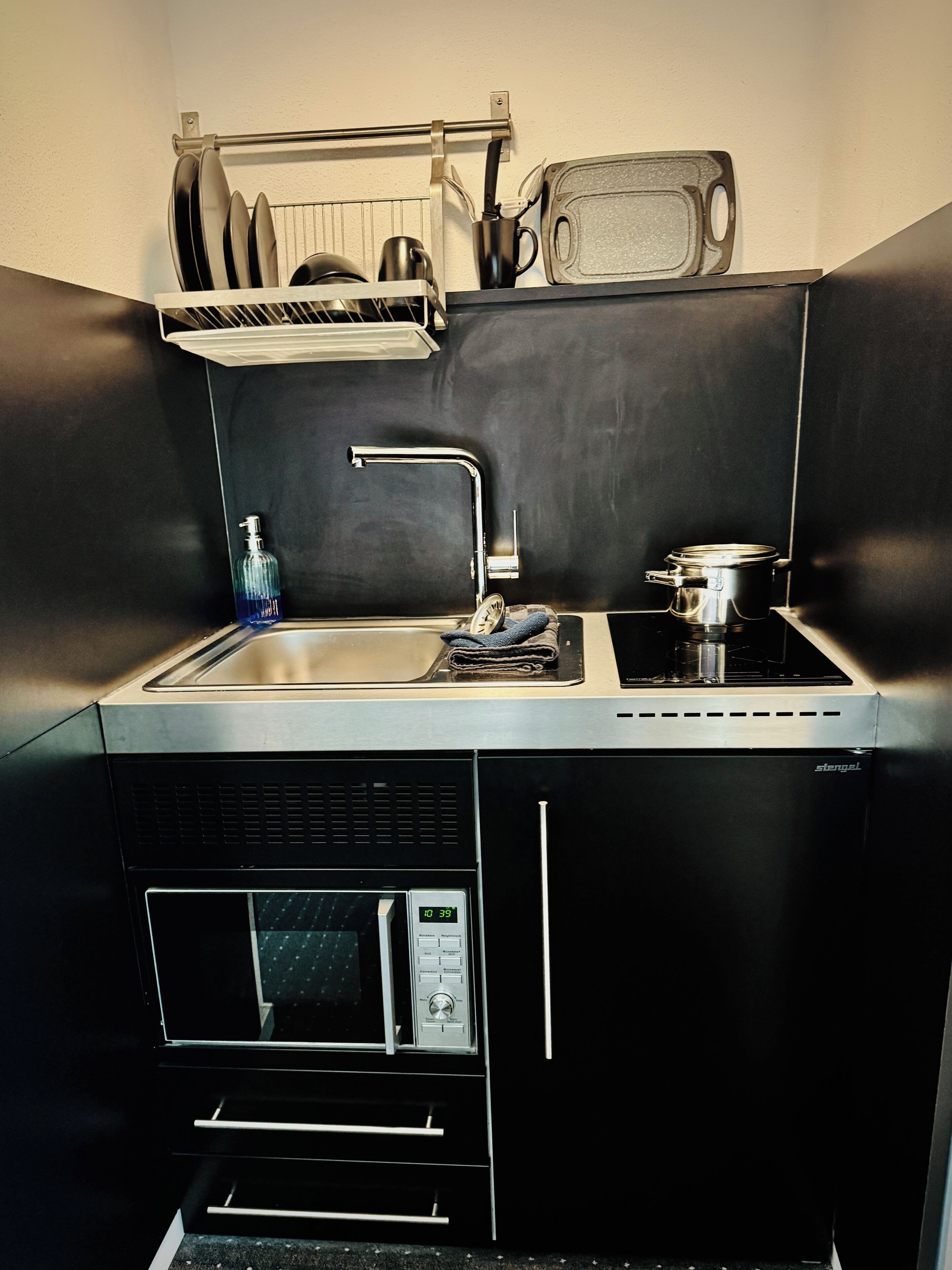 A compact kitchen with a sink, stove, and microwave.