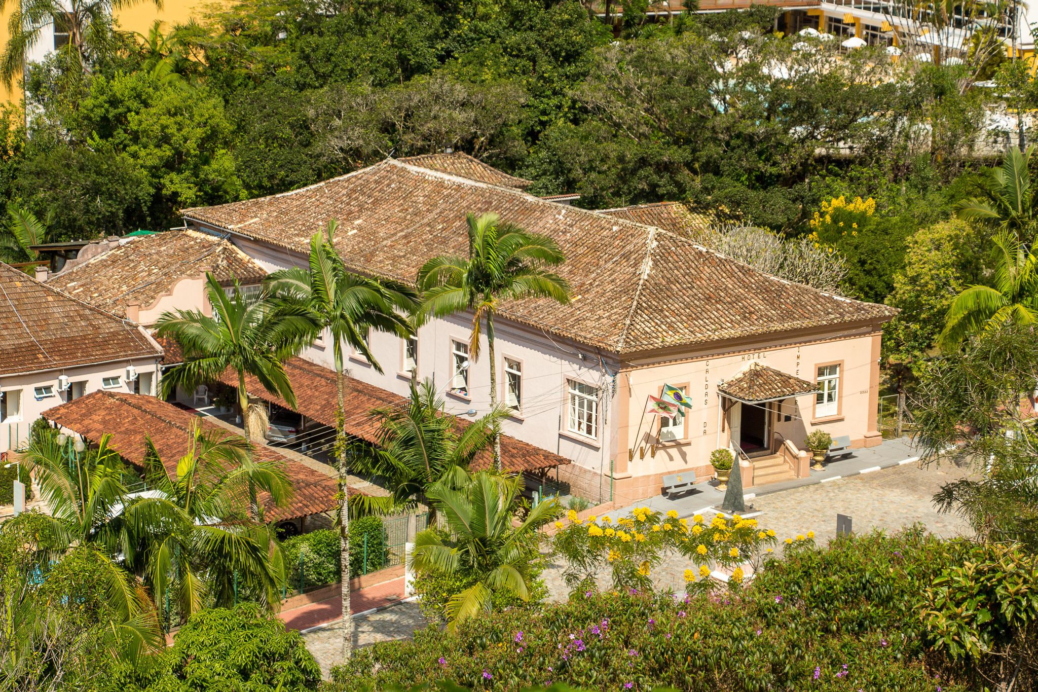 A hotel with a tiled roof, surrounded by lush greenery and palm trees.