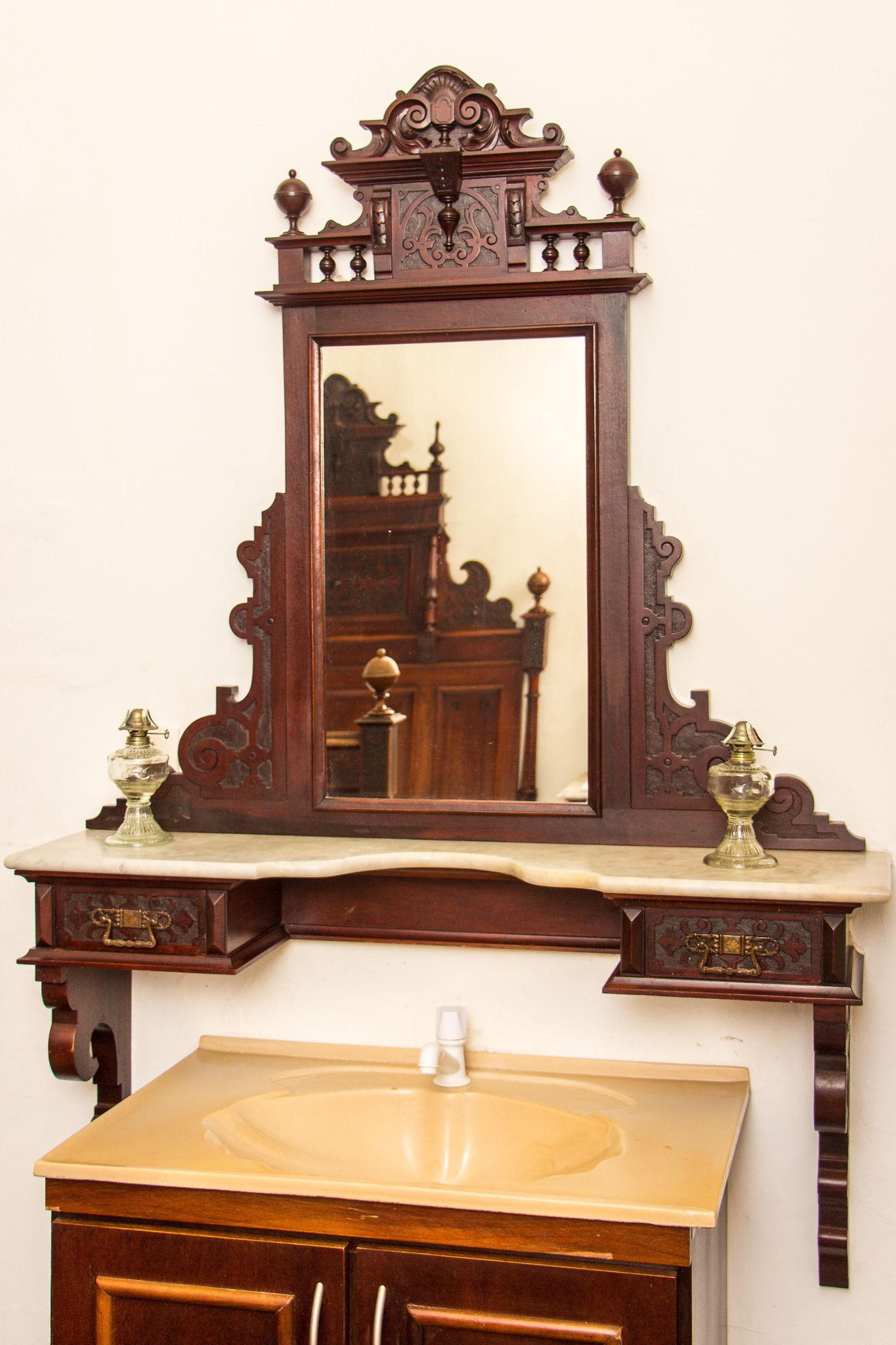A wooden vanity with a mirror, a sink, and two brass fixtures.