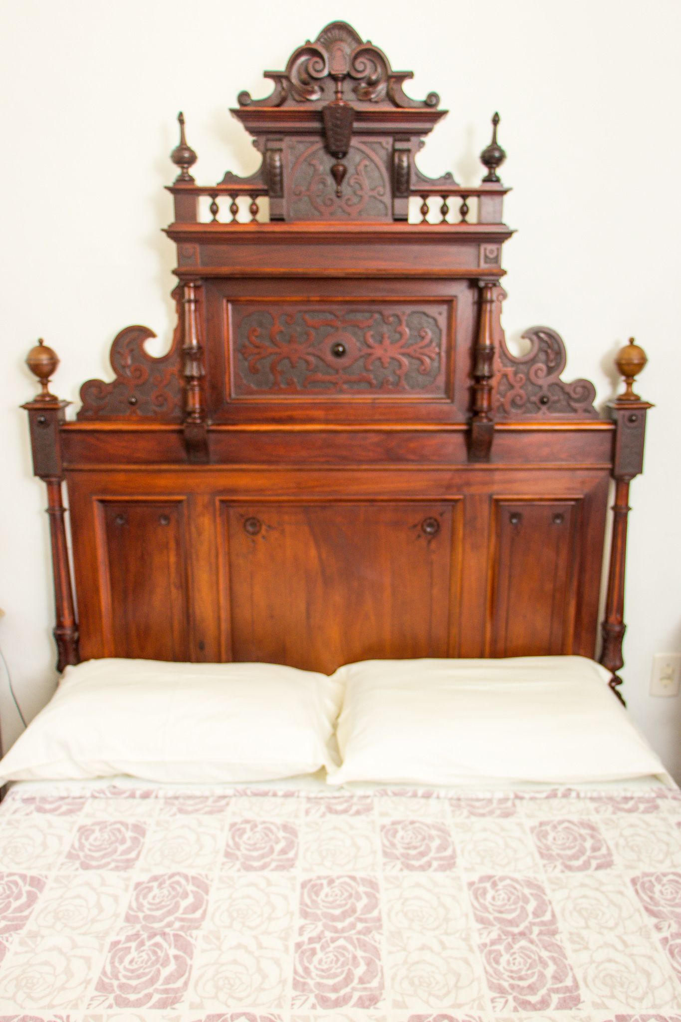 A wooden bed with a floral-patterned bedspread.