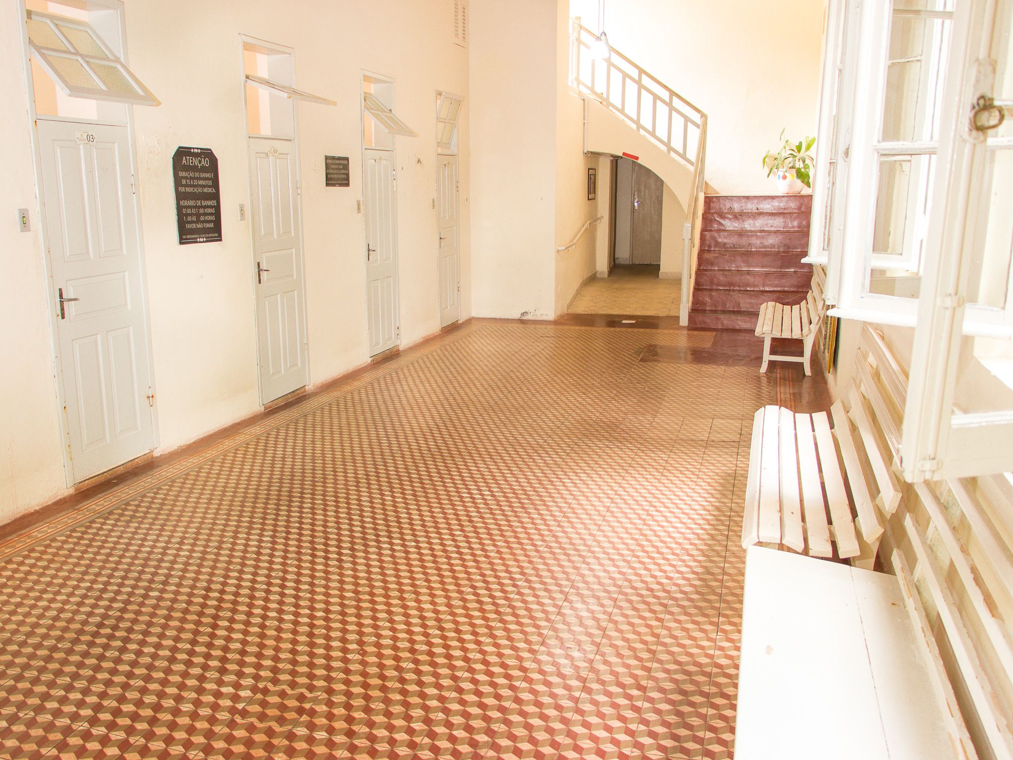 Un couloir doté d’un sol à motifs, de portes blanches et d’un escalier menant à l’étage supérieur.