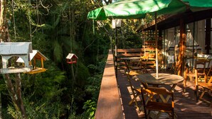 A wooden deck with outdoor seating, surrounded by lush greenery and a small birdhouse. - Hotel Caldas da Imperatriz (Santo Amaro da Imperatriz)