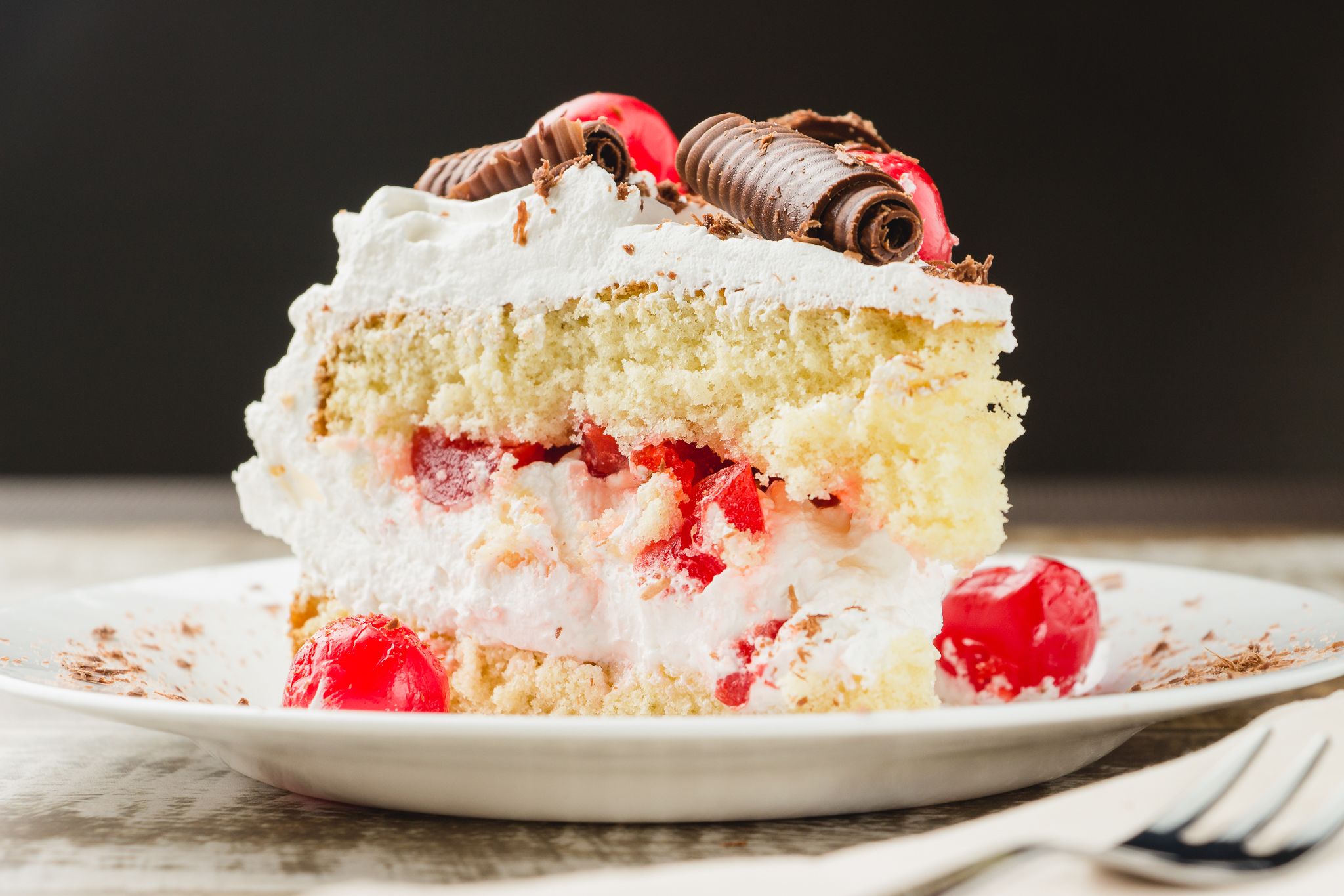 A slice of cake with whipped cream and strawberries on a plate.