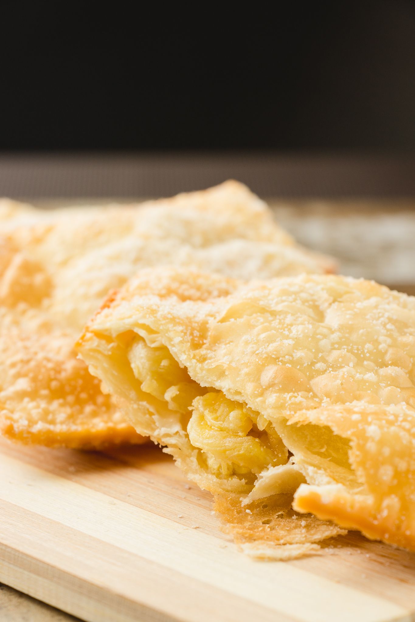 Um doce com crosta dourada, possivelmente uma torta ou pastel, sobre uma superfície de madeira.