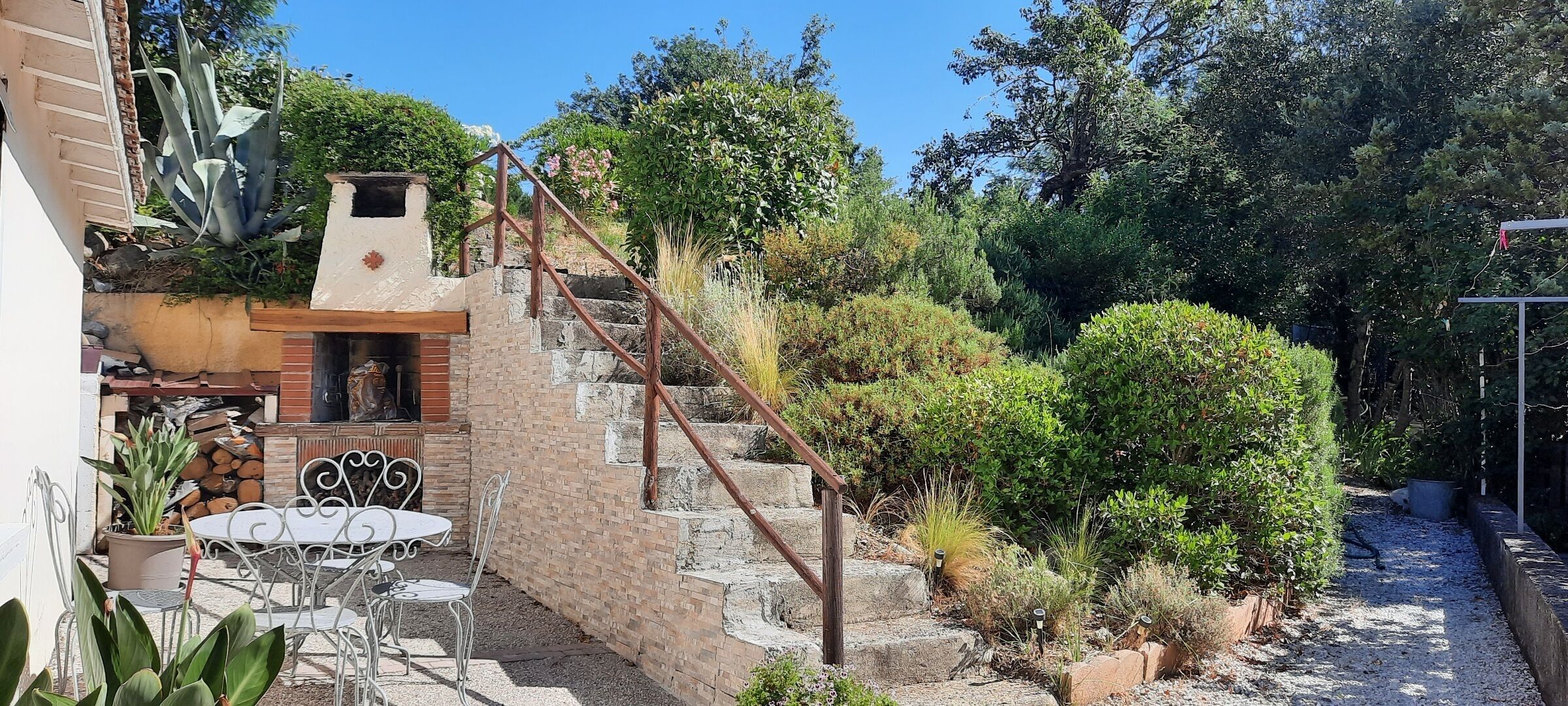 A patio with outdoor seating, a stone staircase, and a variety of plants.