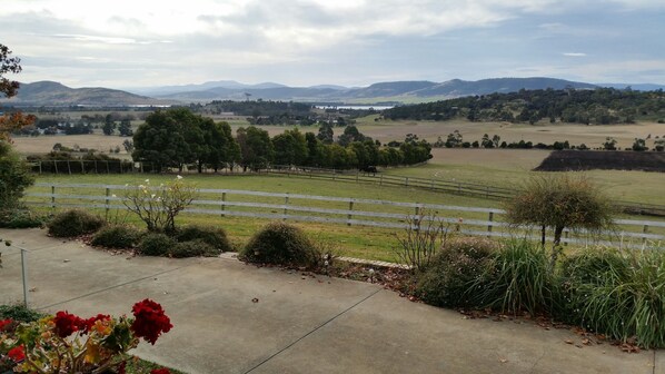 A rural landscape with a fenced pasture, trees, and distant hills.