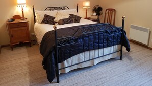 A neatly arranged bedroom with a bed, bedside tables, lamps, and framed pictures on the wall.