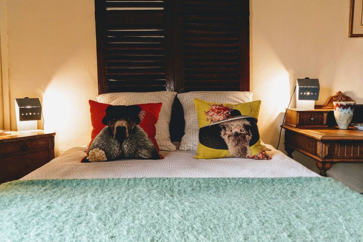 Ein Bett mit zwei Kissen, ein Nachttisch mit einer Lampe und ein Beistelltisch mit einer Lampe.