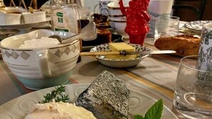 Une table à manger avec une assiette de fromage, un bol de crème glacée et un objet décoratif rouge.