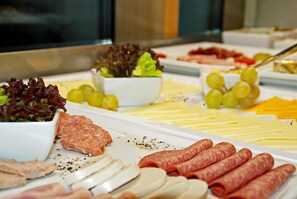 Un bufé con diversas opciones de comida, incluyendo carnes, quesos y ensaladas.