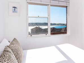 Enjoy a coastal view from the large window, featuring a bed with white bedding and leopard print pillows.