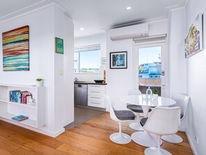 Cozy living space with a bookshelf, dining area, and kitchen, offering a city view.