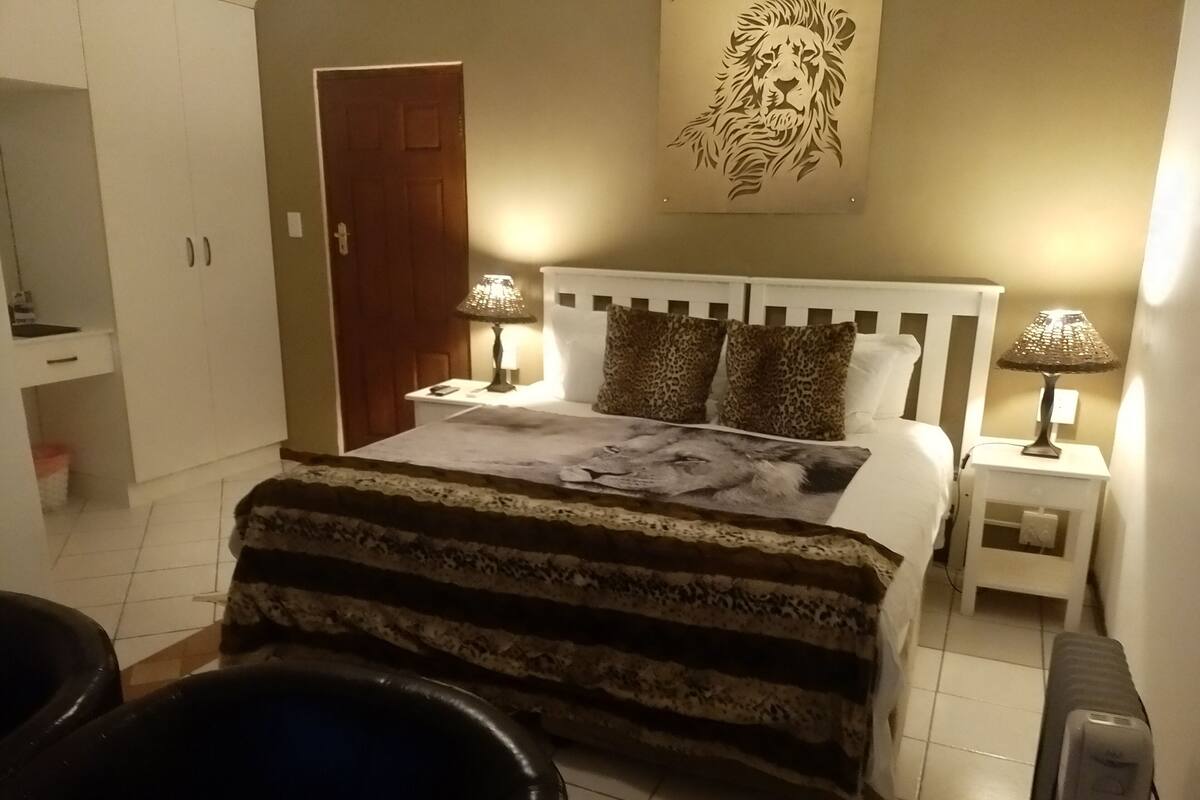 A bedroom with a bed, two nightstands, a lamp, a door, and a wall decoration.