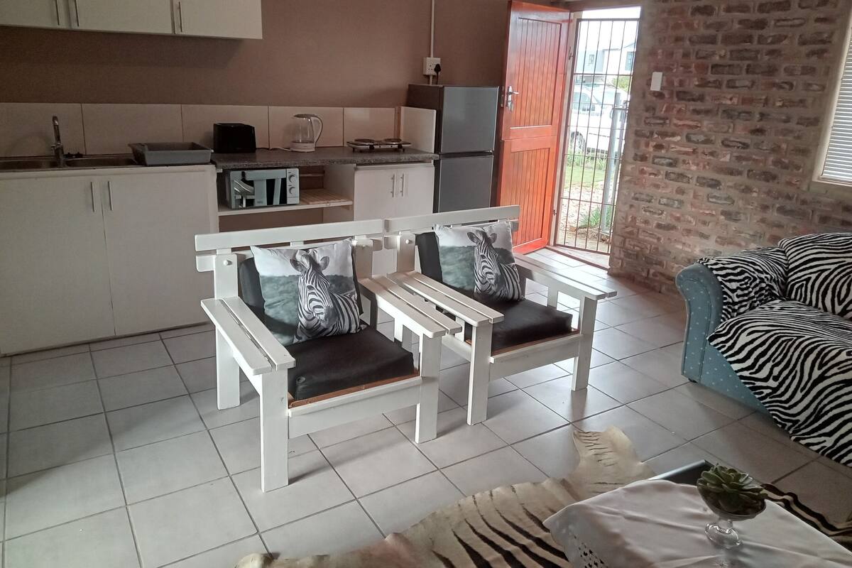 A compact living space with a kitchenette, a zebra-themed sofa, and a dining area.