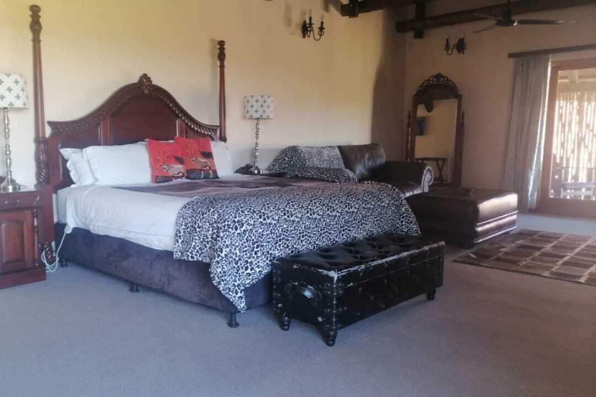 A bedroom with a large bed, a chest of drawers, a nightstand, a lamp, and a mirror.