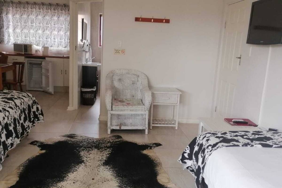 A hotel room with two beds, a large rug, a chair, a desk, and a television.