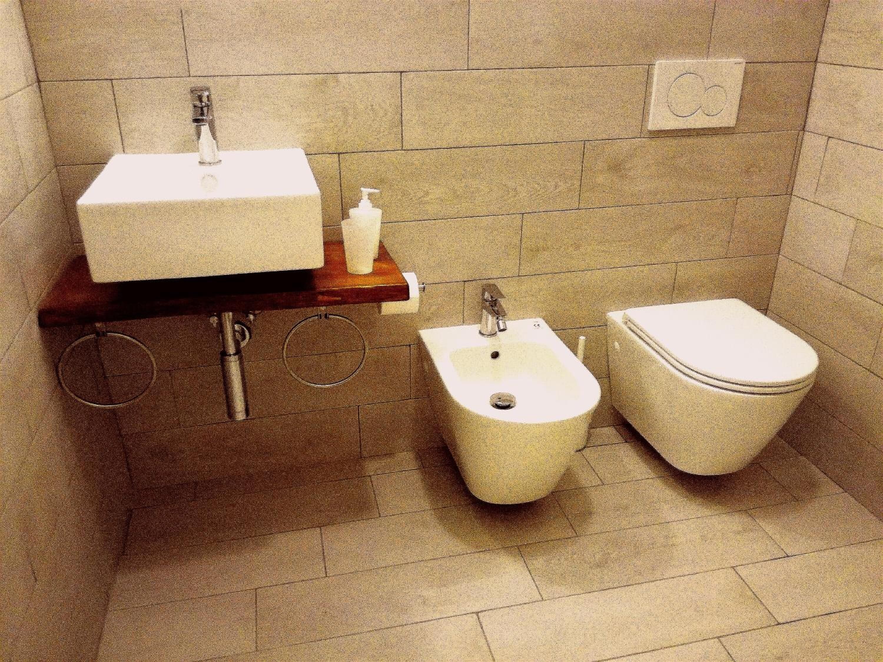 Un baño con lavamanos pedestal, un bidé y un inodoro.