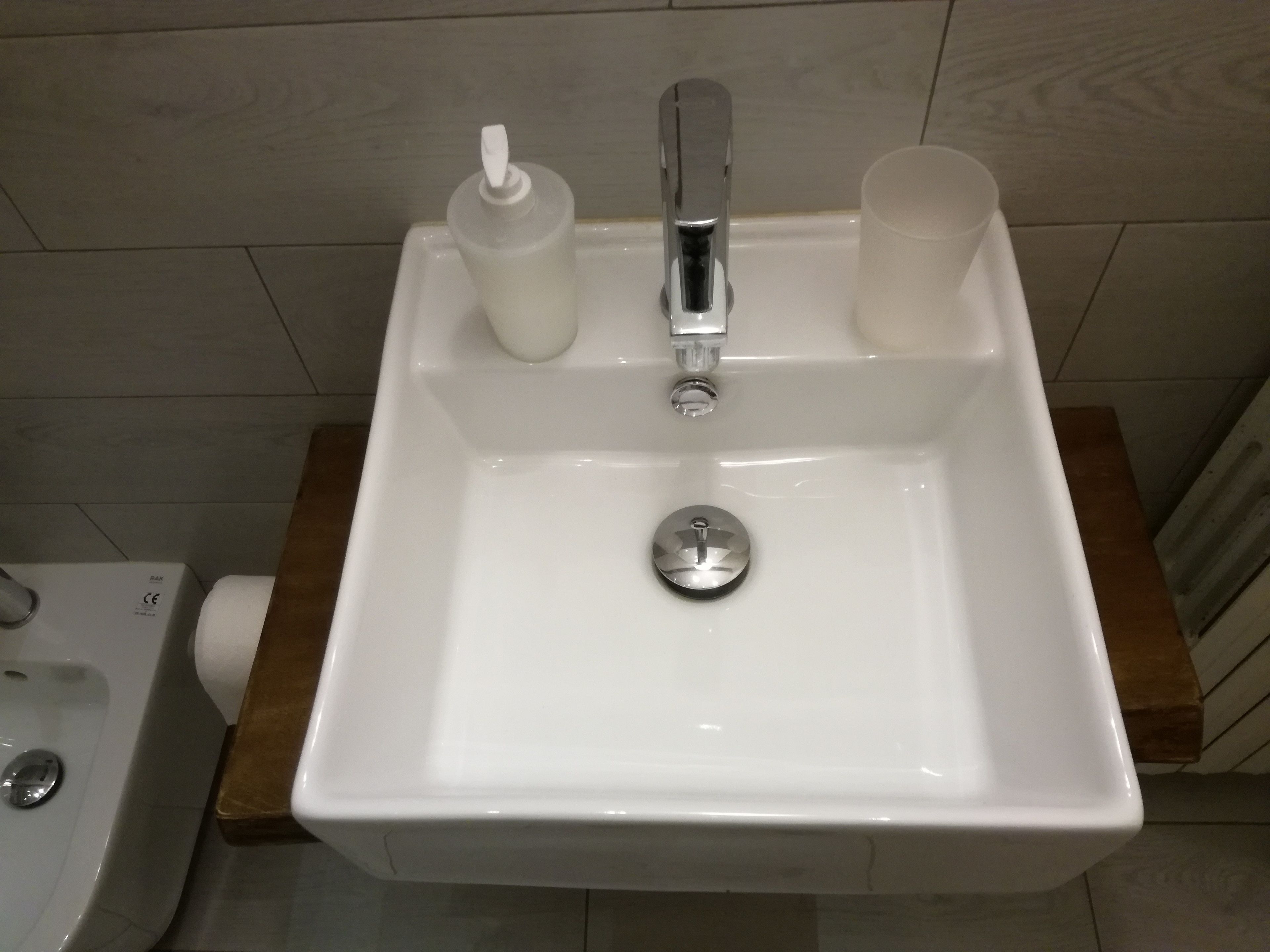 Ein Waschbecken mit Wasserhahn, Seifenspender und einer Tasse.