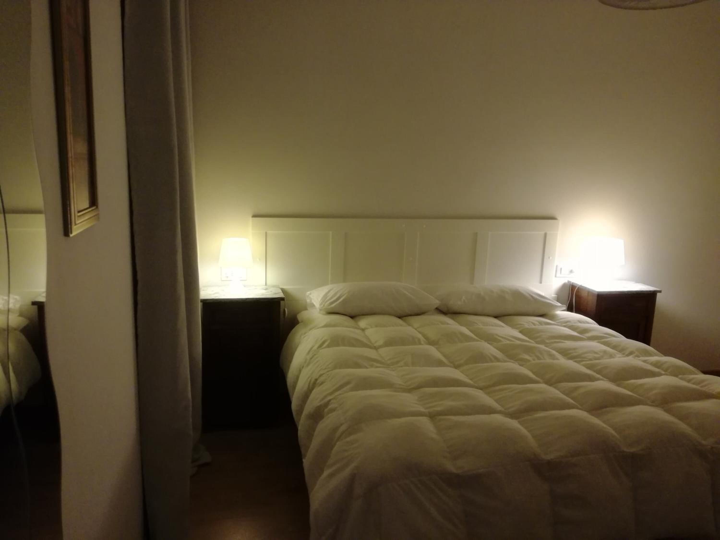A single bed with a white headboard and two bedside tables with lamps.