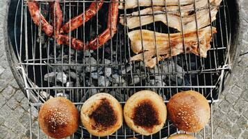 A grill with sausages, ribs, and buns.