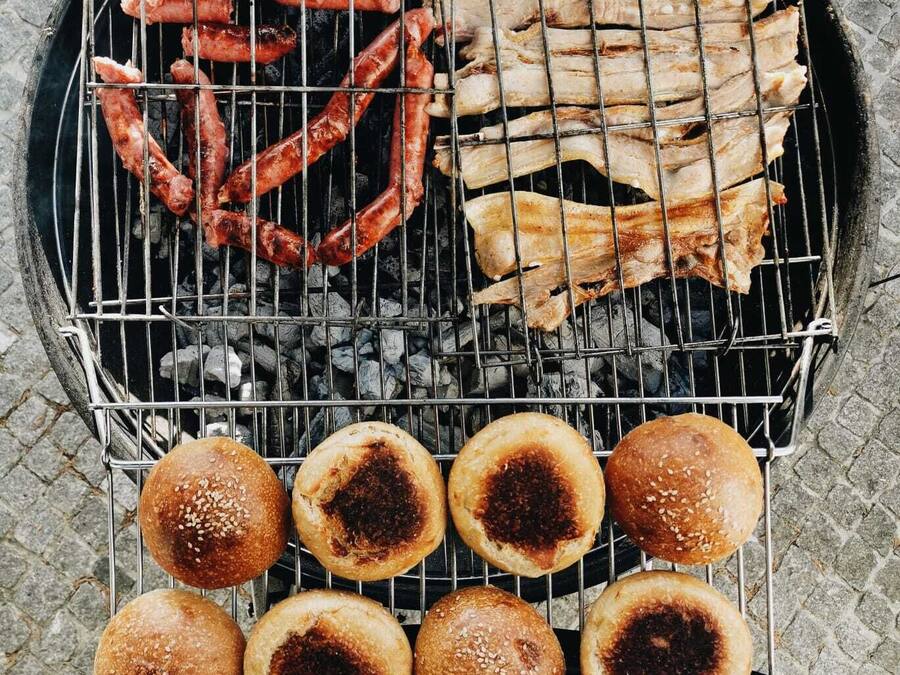 A grill with sausages, ribs, and buns.