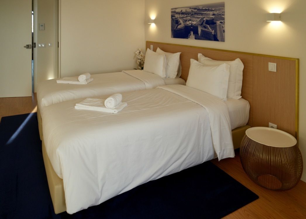 A hotel room with two beds, a round side table, and a painting on the wall.