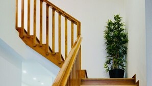 A wooden staircase with a handrail, leading to a landing where a potted plant is placed. - Ó poboa guesthouse (Povoa De Varzim)