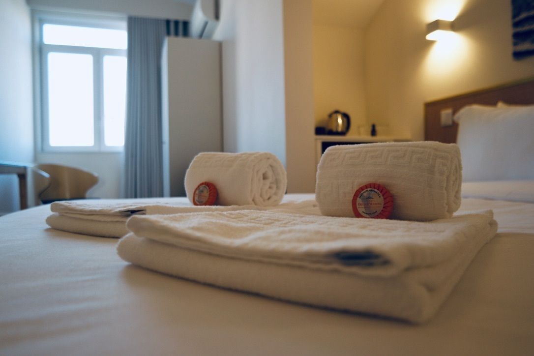 A neatly made bed with folded towels and a visible hotel logo on the pillow.