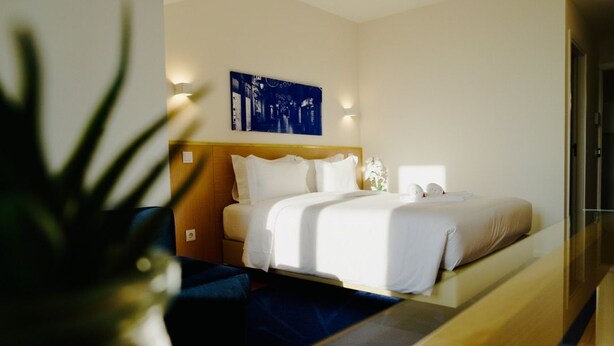 A hotel room with a bed, bedside tables, a wall-mounted artwork, and a potted plant. - Ó poboa guesthouse (Povoa De Varzim)