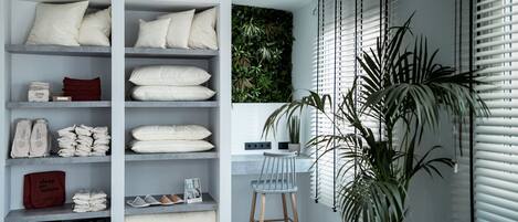 A modern interior with a built-in wardrobe, a small desk with a chair, and a large potted plant.