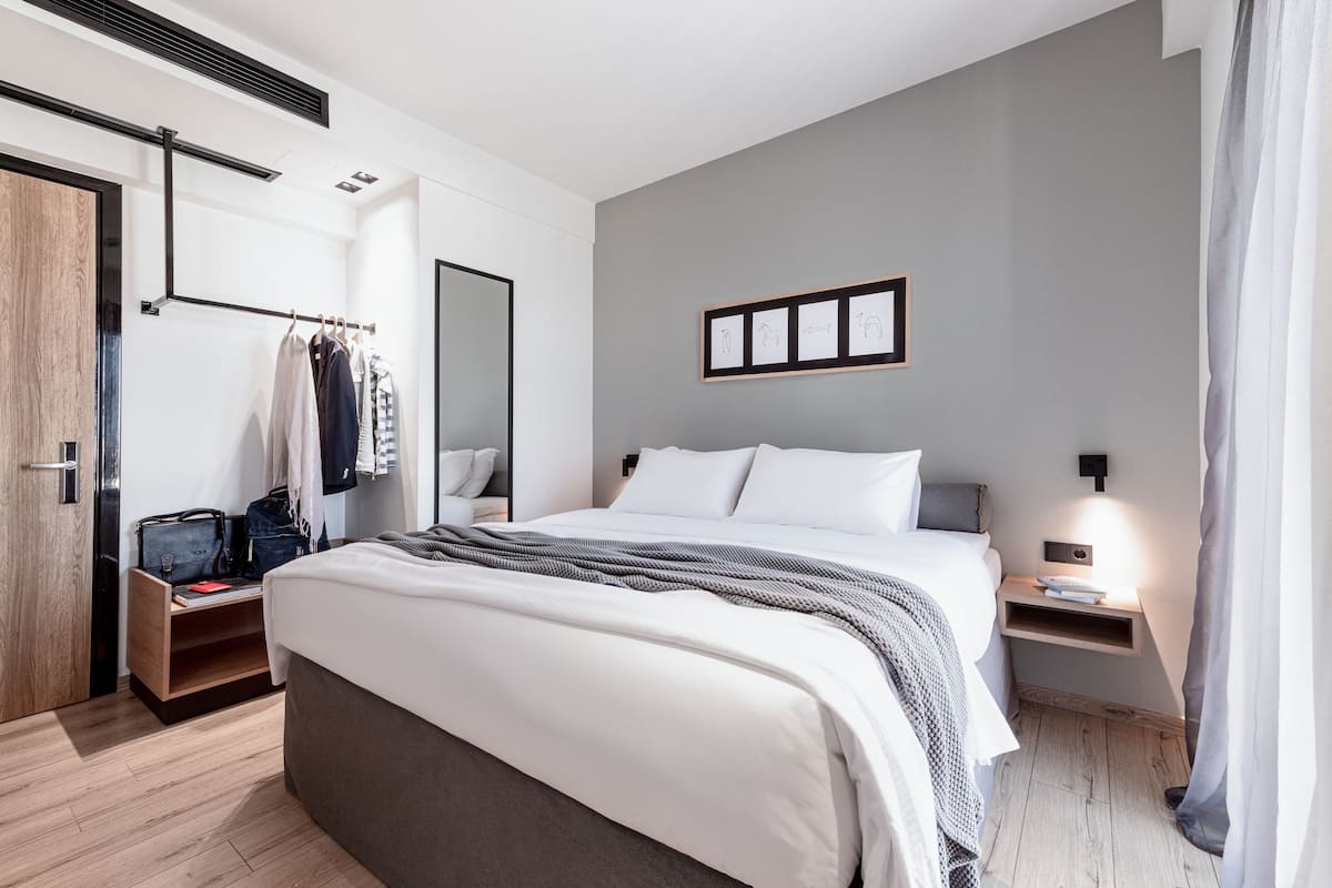 Une chambre moderne avec un grand lit, des tables de chevet, une armoire et un miroir.