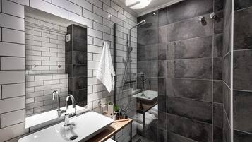 Un baño moderno con un espejo grande, un lavabo, una ducha y una toalla colgada en la pared.