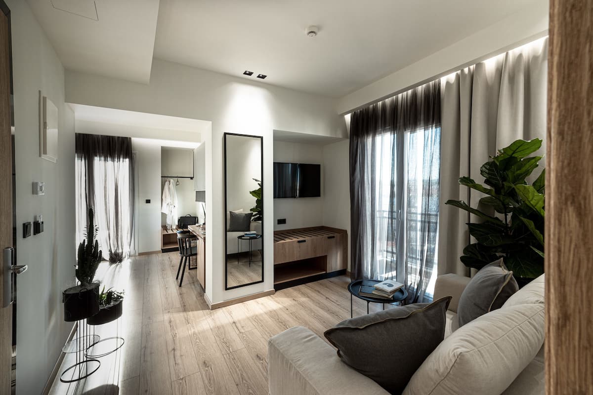 Un salon moderne avec un canapé, une table basse et un téléviseur. On y trouve également un coin repas avec une table et des chaises, ainsi qu’un coin cuisine avec un banc.