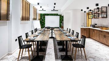 Una sala de conferències amb una taula de fusta llarga, cadires negres i una pissarra al capdamunt.