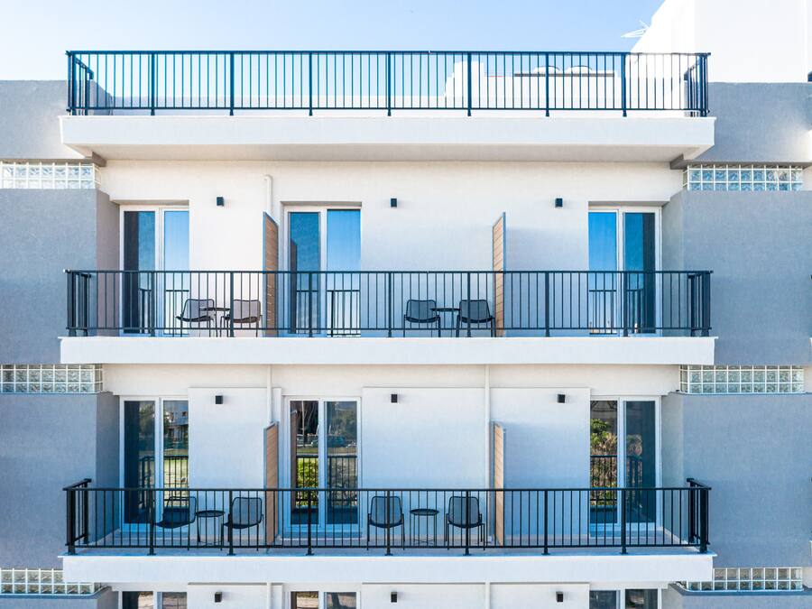 A multi-story hotel with balconies, outdoor seating, and large windows.