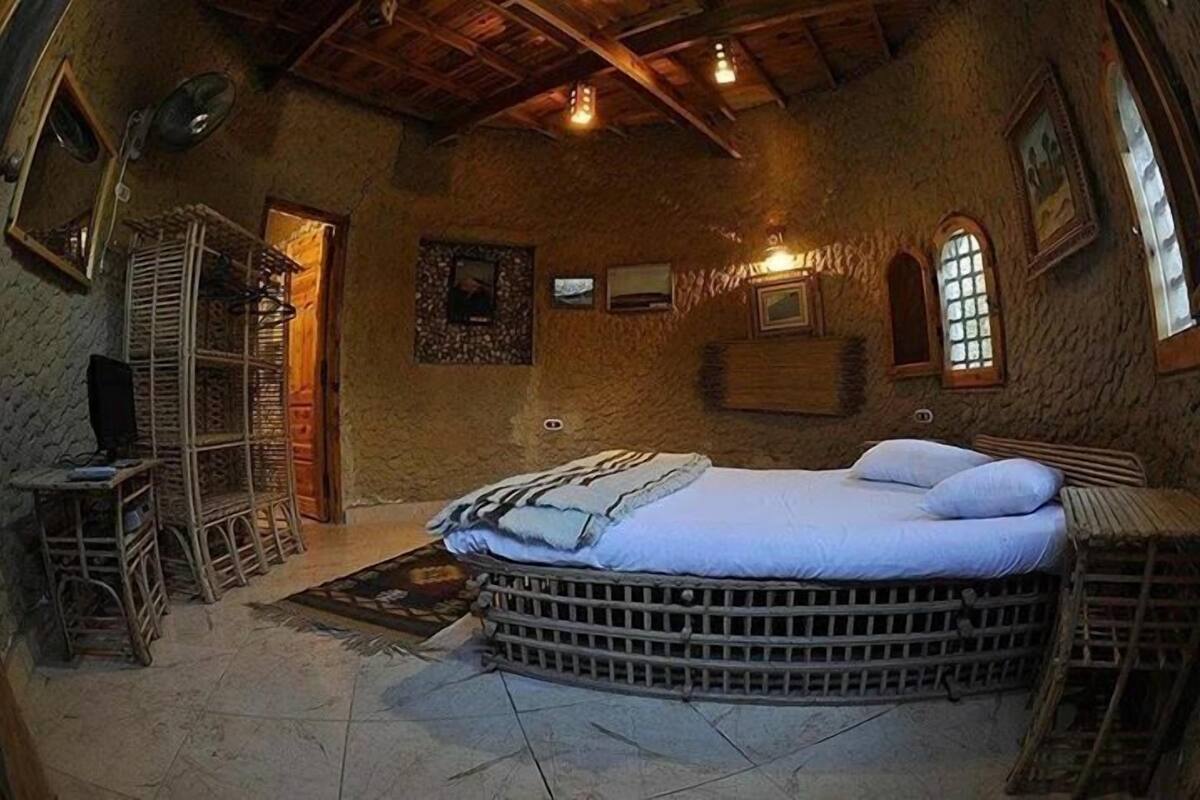 Ein rustikaler Raum mit einem großen Bett, Korbmöbeln und Steinwänden.