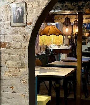 An interior with rustic brick walls, a wooden archway, and tables with chairs. - Bridge House Hotel Bridport (Bridport)
