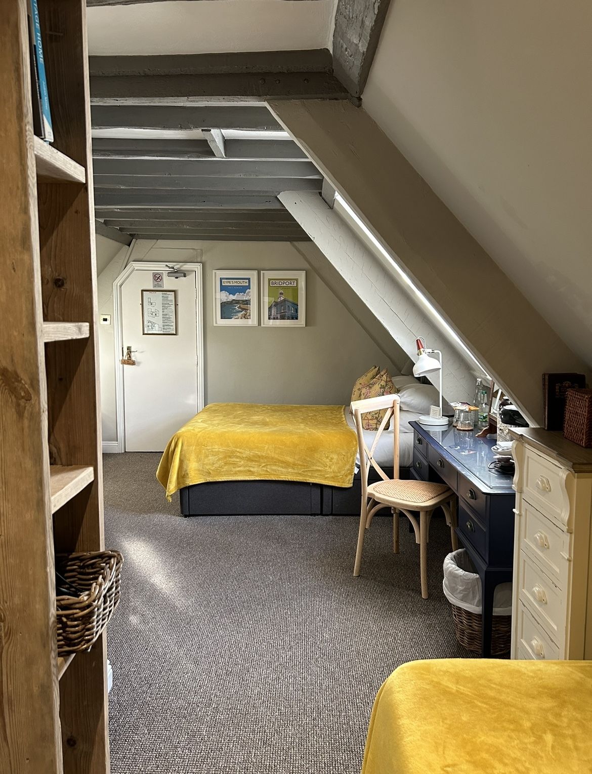 A bedroom with a lofted sleeping area, a desk, a chair, and a bed with a yellow cover.