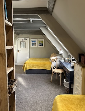 A bedroom with a lofted sleeping area, a desk, a chair, and a bed with a yellow cover.