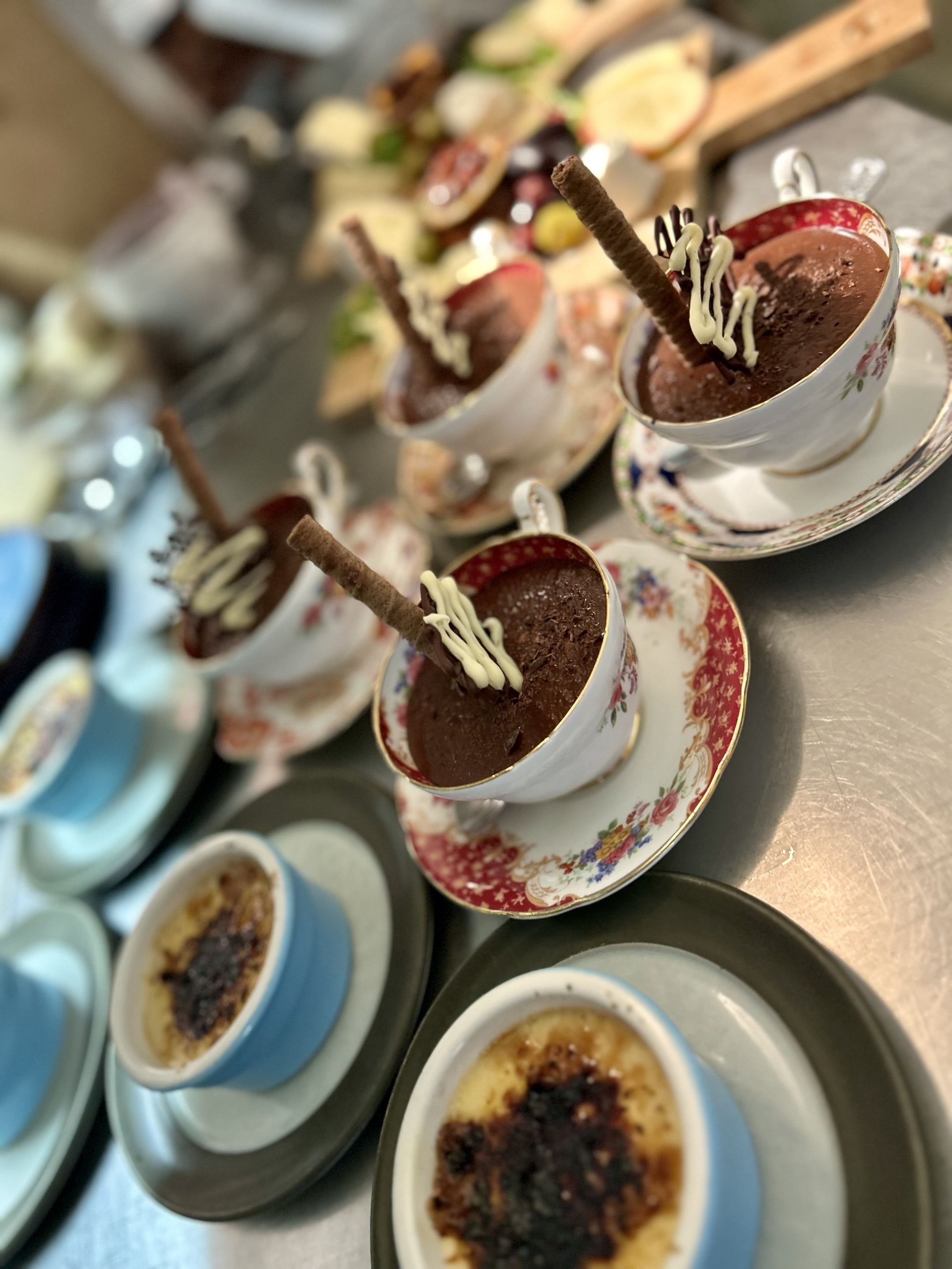 A variety of desserts on a tray, including chocolate mousse with chocolate sticks and cream, and other desserts in different cups.