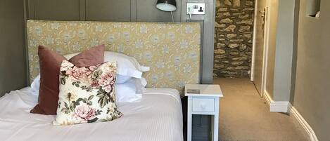 Un dormitorio con cama, mesita de noche, lámpara y alfombra.